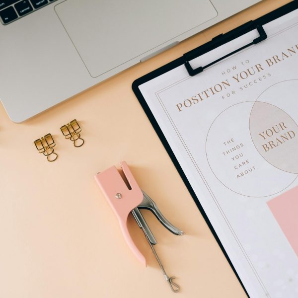 A flat lay composition featuring office essentials and a branding strategy clipboard on a modern workspace.